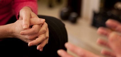 Addiction Recovery Support Meeting Close-up Hands clasped during an addiction recovery meeting, symbolizing support