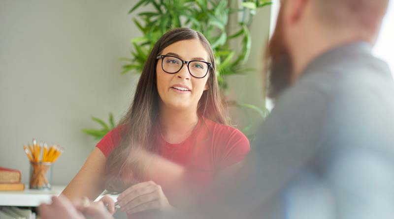 Woman Discussing Alcohol Recovery in Support Group Woman in glasses talking to a man at an alcohol recovery meeting