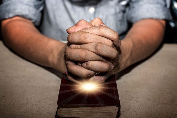 Christian Rehab: Finding Hope Through Faith Hands praying over Bible, symbolizing faith in Christian rehab