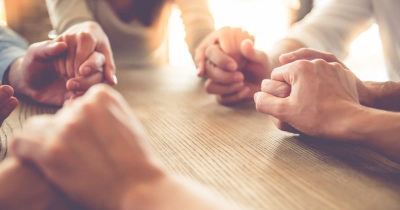 Christian Rehab Support: Finding Faith in Recovery People holding hands in prayer at a Christian rehab meeting.