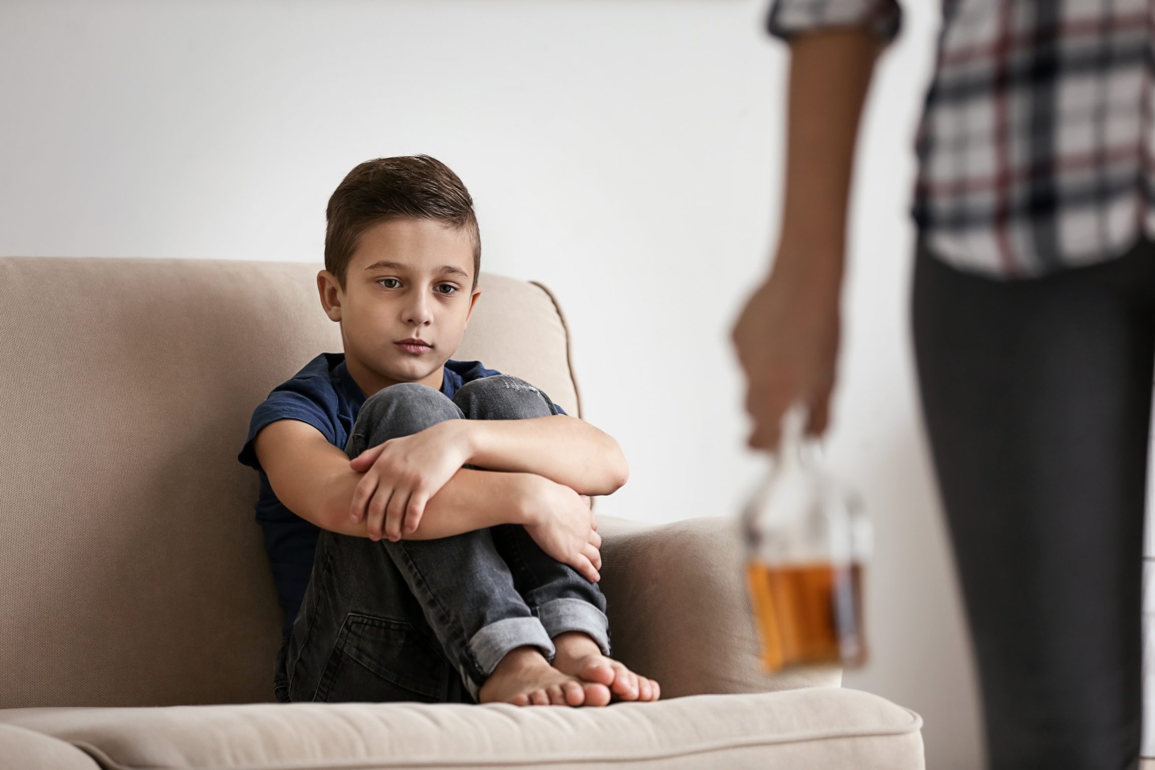 Understanding Addicts Excuses and Family Impact Boy on couch with adult holding bottle, highlighting addicts excuses
